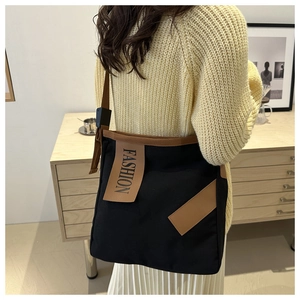 Détail du grand sac cabas en toile noire avec imprimé fashion et bandoulière marron