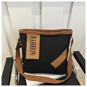Gros plan du sac cabas en toile noire avec étiquette en cuir marron sur un livre