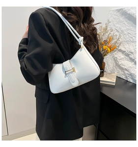 Détail du sac hobo en cuir blanc avec boucle dorée et bandoulière nouée sur blazer noir