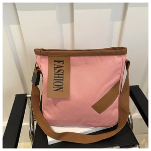 Détail du sac fourre-tout en toile rose avec étiquette mode sur une chaise en cuir