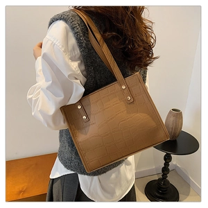 Detail of brown crocodile pattern leather tote bag with sturdy metal rivet reinforcement