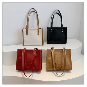 Four different colors of textured crocodile embossed tote bags displayed on a white stand