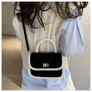 Detail of black quilted shoulder bag with white faux fur trim and gold metal lock