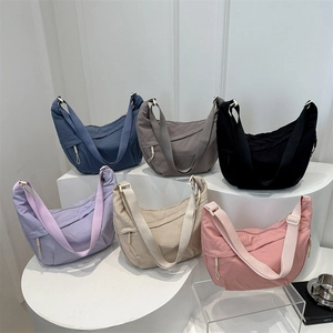 Minimalist nylon crescent crossbody bags in multiple colors shown on display stands
