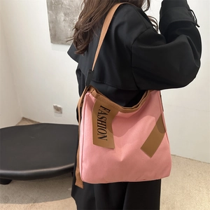 Sac fourre-tout en toile rose avec lanières brunes et écusson de mode sur un mannequin