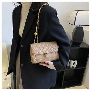 Dettaglio borsa a tracolla trapuntata beige con chiusura a scatto dorata e tracolla a catena