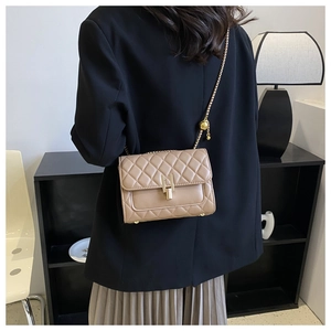 Borsa a tracolla trapuntata beige con catena dorata regolabile indossata su blazer nero