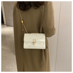 Dettaglio borsa a tracolla trapuntata bianca con catena d'oro su trench coat verde