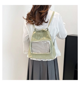 Detail of light green pleated backpack with transparent front pocket on a person