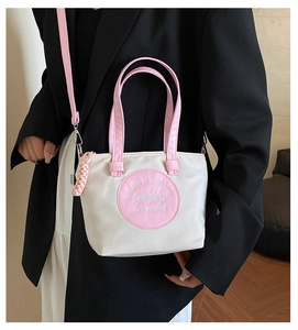 Détail du sac cabas en nylon contrasté avec anses roses et patch logo décoratif