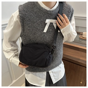 Detail of adjustable nylon strap and pleated texture on this black crossbody bag