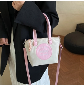 Détail du sac cabas en nylon blanc avec anses roses et broderie décorative