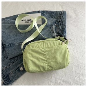 Detail of light green nylon crossbody bag with wide shoulder strap and fabric texture