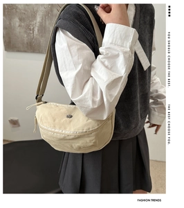 Close-up of cream nylon crossbody bag with adjustable wide strap on a model
