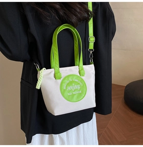 Détail du sac bandoulière en toile avec sangles vert néon et broderie enjoy
