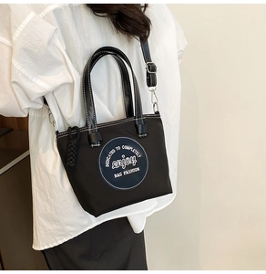 Détail du sac fourre-tout en nylon noir avec surpiqûres blanches et écusson logo