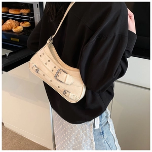 Détail du sac beige en forme de croissant avec œillets métalliques et boucles