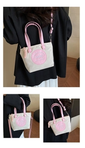 Détail du sac fourre-tout en nylon bicolore montrant le logo brodé rose et la bandoulière