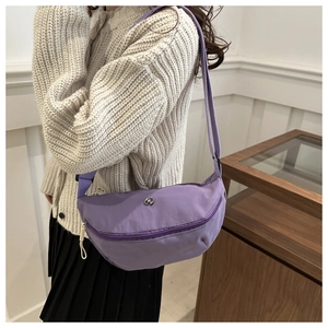 Detail view of purple crescent crossbody bag with adjustable wide strap on model