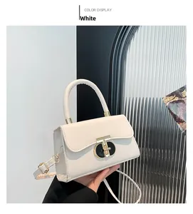 Close-up of white crossbody bag with golden T-lock and smooth faux leather texture
