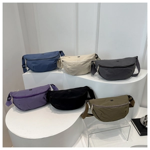 Multiple colorful nylon crescent bags displayed on white pedestals in a row