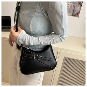 Detalle de bolso bajo el brazo minimalista negro con hebilla plateada y correa ajustable