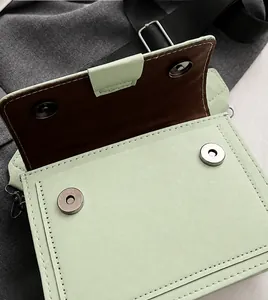 Close-up of dual silver magnetic buckles and neat stitching on light green faux leather bag