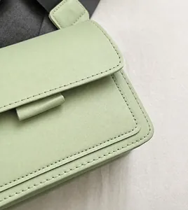 Detail of mint green leather bag showing handmade stitching and smooth edge finish