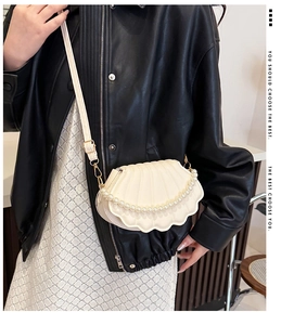 Detail of shell-shaped evening bag with pleat textures and elegant pearl handle ornament