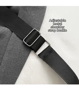 Detail of adjustable silver metal buckle on black nylon shoulder strap of a handbag