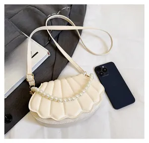 Detail of shell-shaped evening bag featuring fan quilting and decorative pearl chain