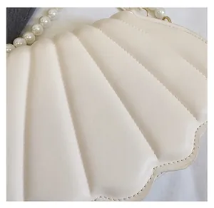 Detailed view of cream shell bag with quilted texture and large pearl handle strap