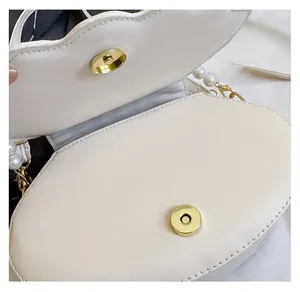 Detailed close-up of the high-quality magnetic clasp and cream leather shell bag interior