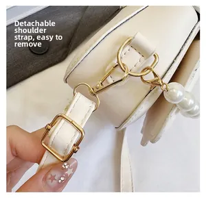 Detail of detachable shoulder strap with golden lobster clasp and decorative pearl bead