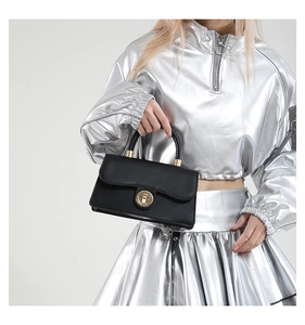 Detail of minimalist black matte leather handbag with elegant golden circular metal twist lock