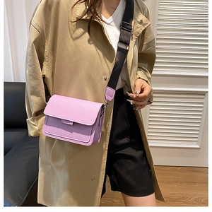Lavender flap crossbody bag with wide black strap styled on a tan trench coat