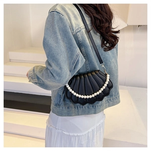 Detailed view of black shell bag featuring large white pearl handle and PU leather pleats