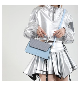 Close-up of contrast color handbag with silver metal handle worn by model in a studio