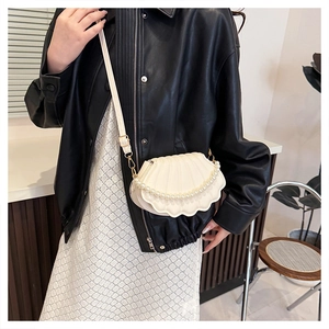 Detail of shell-shaped crossbody bag with pearl strap and matte PU leather texture