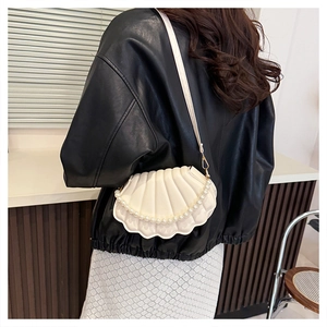 Detail of shell-shaped crossbody bag in cream white with pleated texture and pearl chain