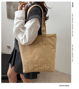 Close-up of the KTMU textured embroidery on a light brown canvas tote shoulder bag