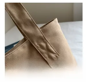 Detail of khaki canvas tote bag showing heavy-duty reinforced X-stitch on shoulder straps