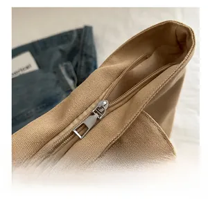 Detailed macro view of smooth metal zipper on durable beige canvas tote bag surface