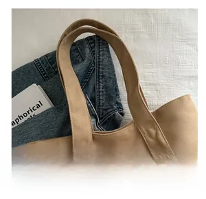 Detail of cross-stitched reinforcement on light brown canvas tote bag straps