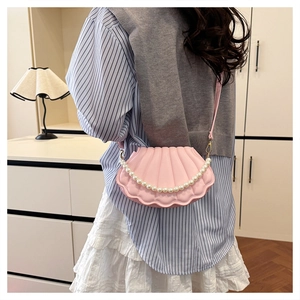 Detail of pink shell-shaped crossbody bag with pearl chain strap and pleated leather texture
