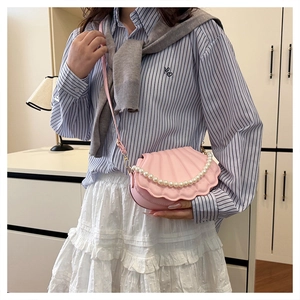 Detail view of pink shell-shaped crossbody bag with pearl chain and detachable strap