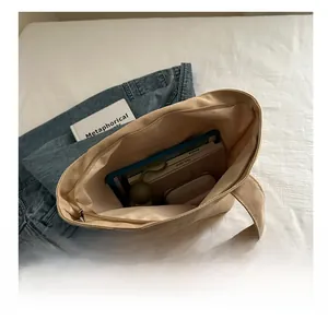 Macro view showing spacious interior of beige canvas tote bag with books and a tablet