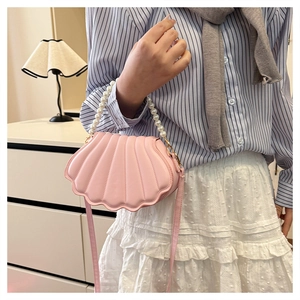 Detail of shell-shaped pink bag featuring faux pearl handle and ribbed texture