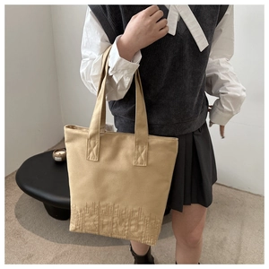 Detail shot of khaki canvas tote bag featuring elegant bottom embroidery and sturdy straps