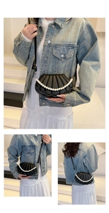 Detail of black shell-shaped leather crossbody bag featuring pearl handle and pleated texture